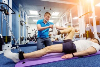Man doing exercises on a mat under the supervision of a physiotherapist